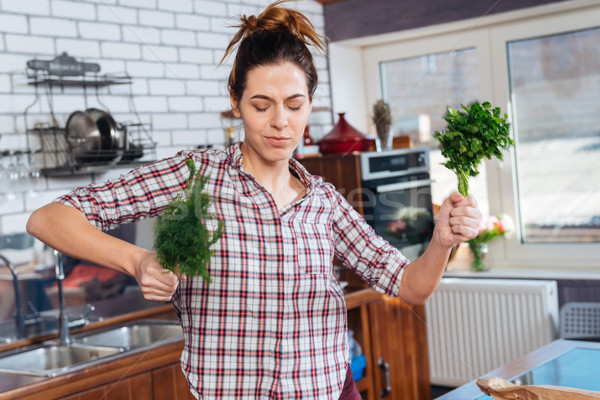 Happy woman holding dill and dacing on the kitchen Stock photo © deandrobot