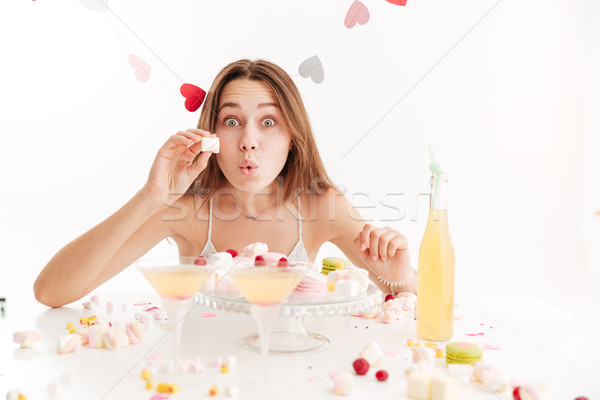 Amazed woman showing and eating marshmallows at holiday table Stock photo © deandrobot
