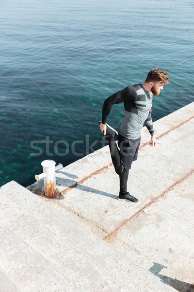 Young runner warming up in harbor Stock photo © deandrobot