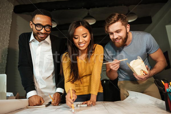 Cheerful architects working at night while eating Stock photo © deandrobot