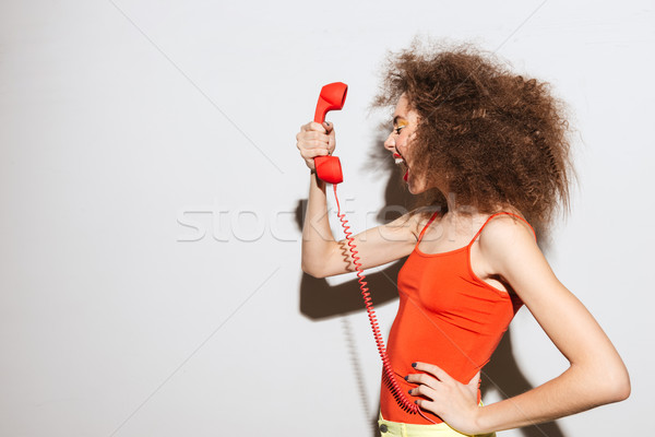 Side view of Unusual model screaming at handset Stock photo © deandrobot
