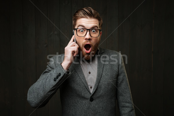 Zdziwiony zdziwiony człowiek okulary mówić telefonu komórkowego Zdjęcia stock © deandrobot