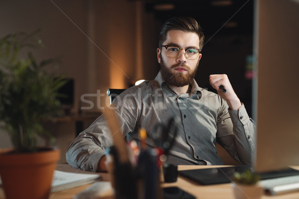 Serious web designer working at night and looking to camera Stock photo © deandrobot
