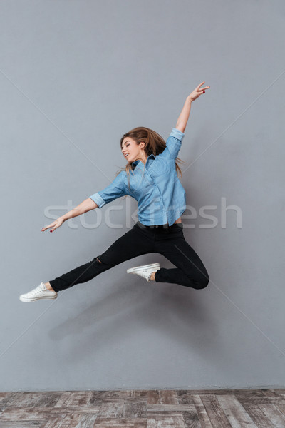 Full length portrait of woman in shirt jumping in studio Stock photo © deandrobot