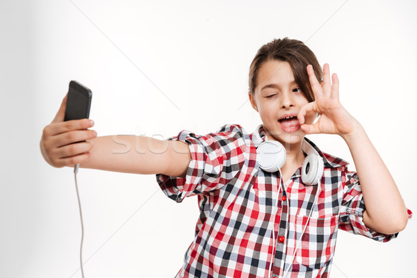 Funny girl in shirt and with headphone making selfie Stock photo © deandrobot