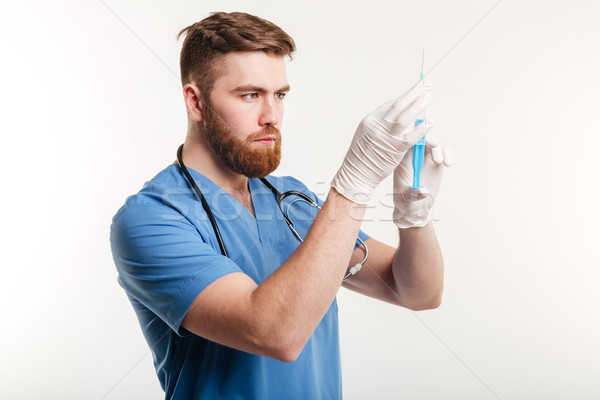 Portrait of a serious surgeon holding a syringe Stock photo © deandrobot