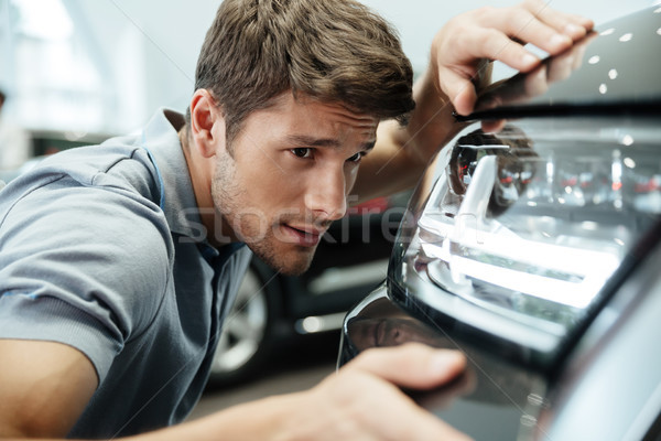Male customer examining and looking carefully at a new car Stock photo © deandrobot