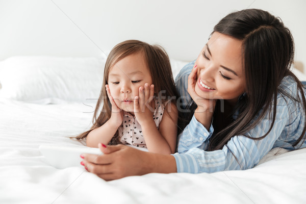 Stock photo: Amazing young woman with little daughter using mobile phone.