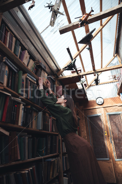 Young woman searching book in library Stock photo © deandrobot