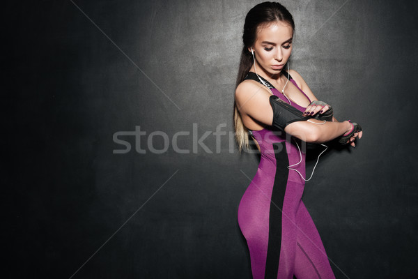 Young fitness woman with earphones adjusting her mobile phone Stock photo © deandrobot