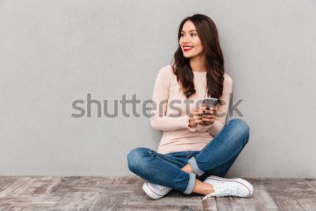 Contented smiling woman with red lips typing text message or scr Stock photo © deandrobot