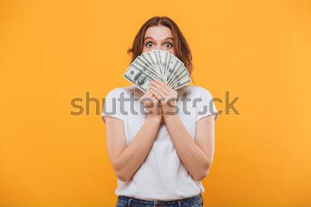 Emotional young pretty woman holding money covering face. Stock photo © deandrobot