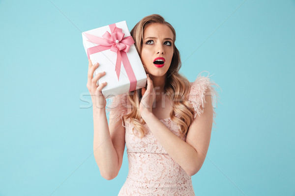 Intrigued blonde woman in dress holding gift and looking up Stock photo © deandrobot