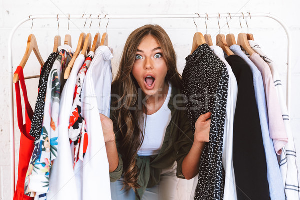 Izgatott fiatal nő ruházat designer áll ruhaakasztó Stock fotó © deandrobot