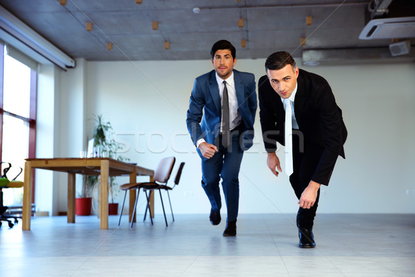 Two businessman running together in office. Business concept Stock photo © deandrobot