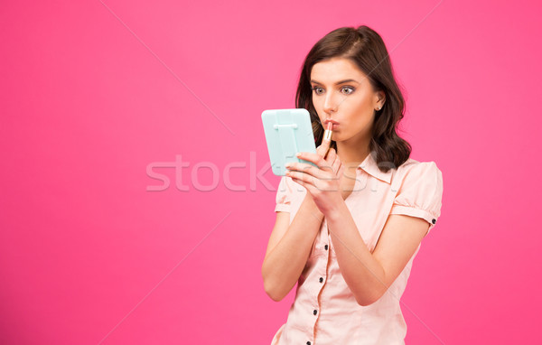 Young woman putting lipstick on lips Stock photo © deandrobot