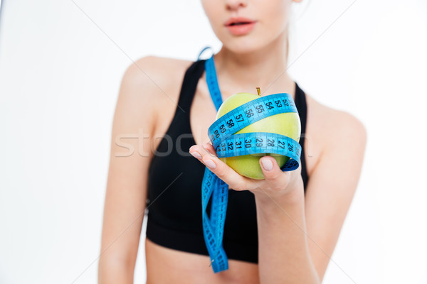 Apple with blue measuring tape holded by sportswoman Stock photo © deandrobot