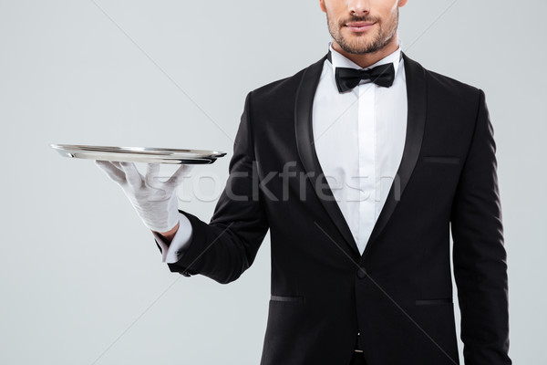 Closeup of waiter in tuxedo and gloves holding silver tray Stock photo © deandrobot