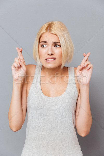 Portrait of worried anxious young woman with fingers crossed Stock photo © deandrobot