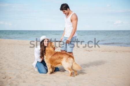 Couple in love playing with their dog on the beach Stock photo © deandrobot