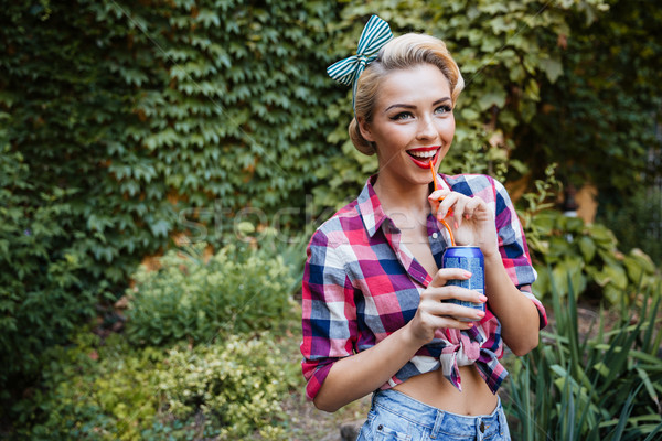 Cheerful pinup girl walking in park and drinking soda Stock photo © deandrobot