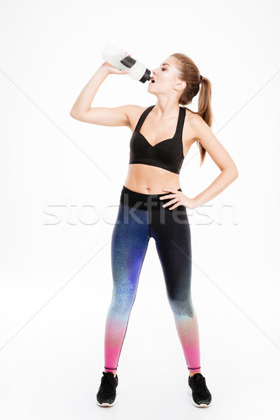 Full length portrait of a beautiful sports woman drinking water Stock photo © deandrobot