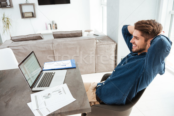 Happy young man stretching at home near laptop Stock photo © deandrobot