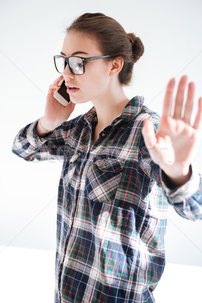 Beautiful woman talking on cell phone and showing stop gesture Stock photo © deandrobot