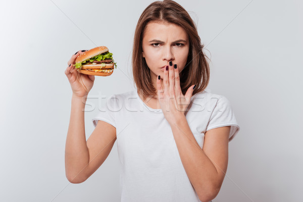 Angry woman holding fastfood and covering mouth Stock photo © deandrobot