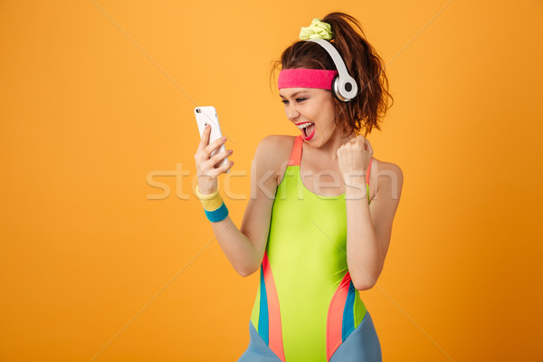 Happy fitness woman in earphones listening to music from smartphone Stock photo © deandrobot