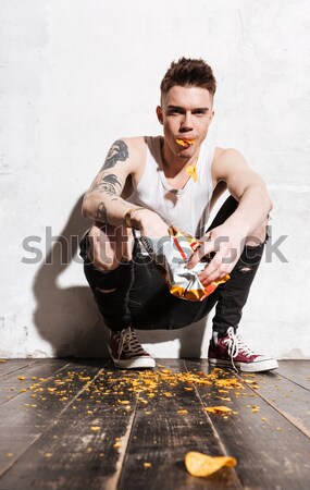 Grappig jonge man vergadering chips vloer Stockfoto © deandrobot