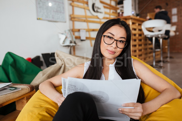 Woman sitting in bean bag chair and working with papers Stock photo © deandrobot