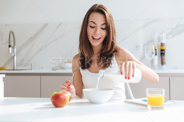 Happy joyful woman pouring milk into a bowl Stock photo © deandrobot