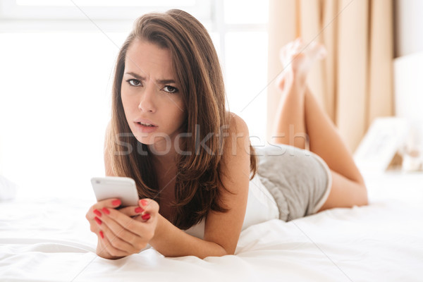 Close up portrait of upset disappointed woman holding mobile phone Stock photo © deandrobot