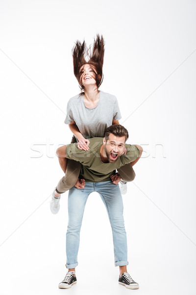 Woman shaking her hair while sitting on man's back Stock photo © deandrobot