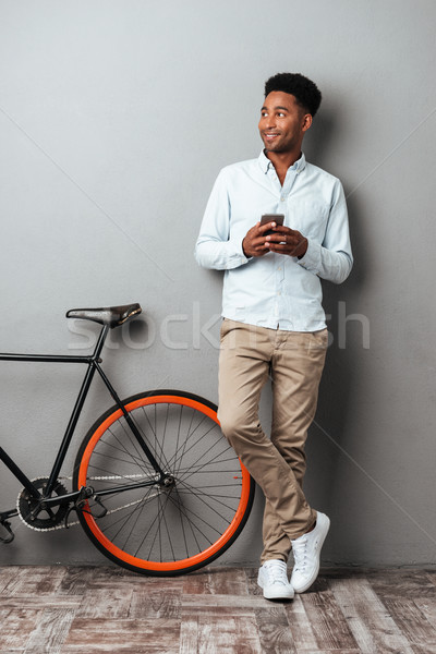 Cheerful young african man chatting by phone. Stock photo © deandrobot