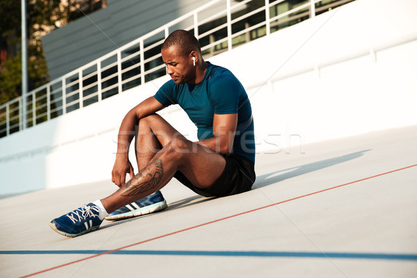Portrait of a serious african fitness man in earphones resting Stock photo © deandrobot
