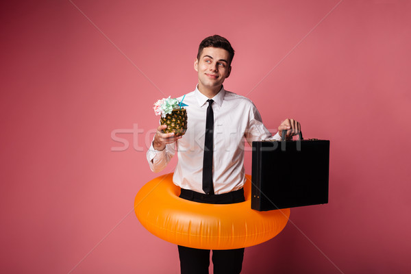 Young man holding brief-case and cocktail and dreaming about rest Stock photo © deandrobot