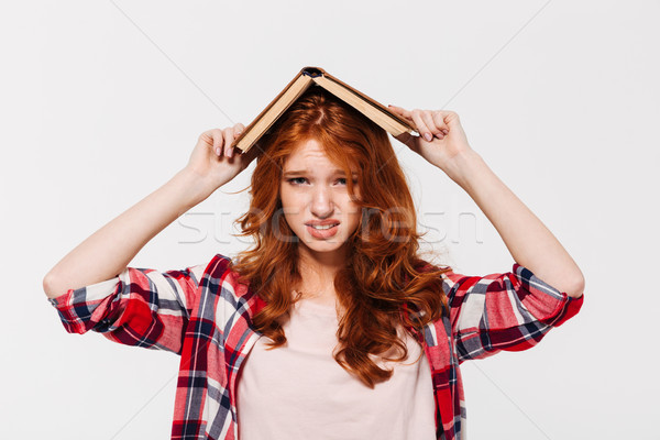 Displeased ginger woman in shirt holding book on her head Stock photo © deandrobot