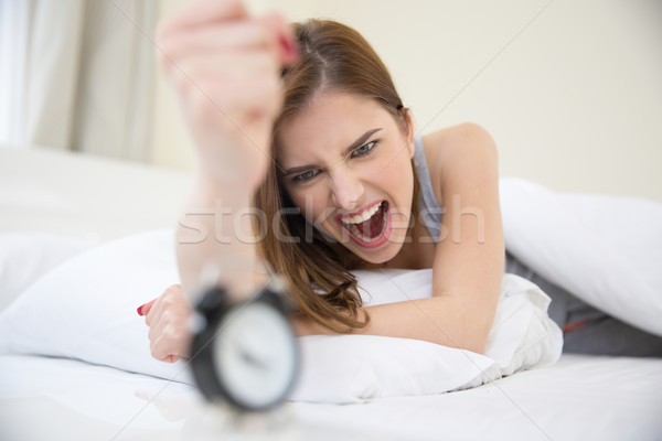 Angry woman who woke up very early to call an alarm clock in the bedroom Stock photo © deandrobot