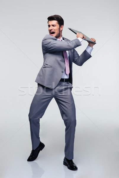 Angry businessman trying to smash his laptop Stock photo © deandrobot