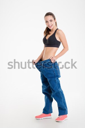 Fitness girl in big jeans showing result of weight loss  Stock photo © deandrobot