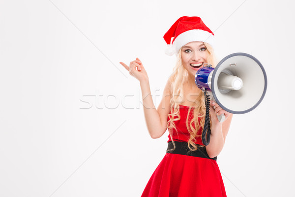 Beautiful cheerful young woman talking in speaker and pointing away  Stock photo © deandrobot