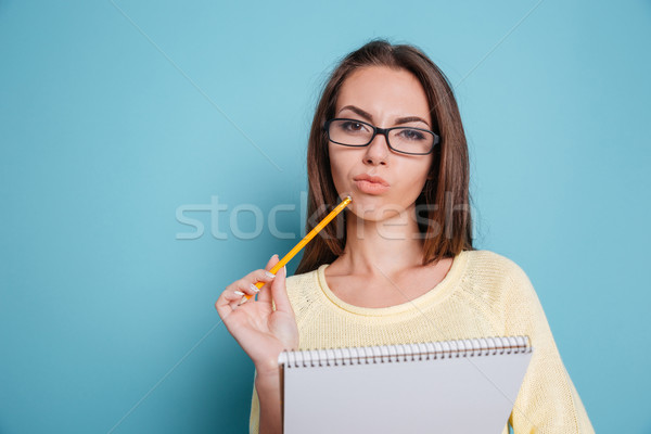 Pensive smart girl thinking about something and holding notebook Stock photo © deandrobot