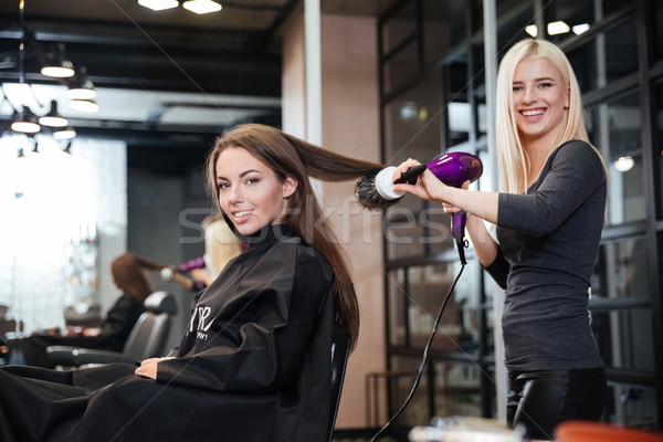 Woman and hairdresser with fan making hot styling at salon Stock photo © deandrobot