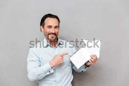 Smiling lovely young businesswoman standing and holding laptop Stock photo © deandrobot