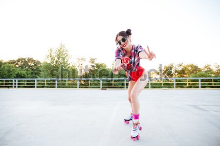 Stock photo: Happy young woman riding on roller skates outdoors