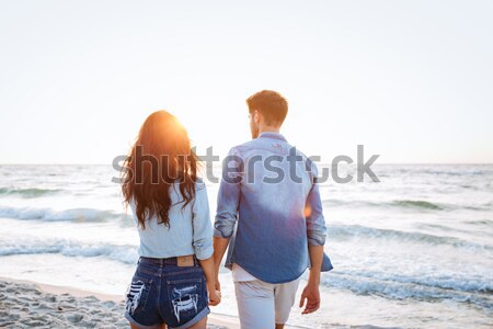 Couple walking at sunrise on the beach Stock photo © deandrobot