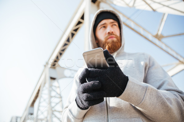 Stock photo: Man in hoodie standing at the bridge with mobile phone