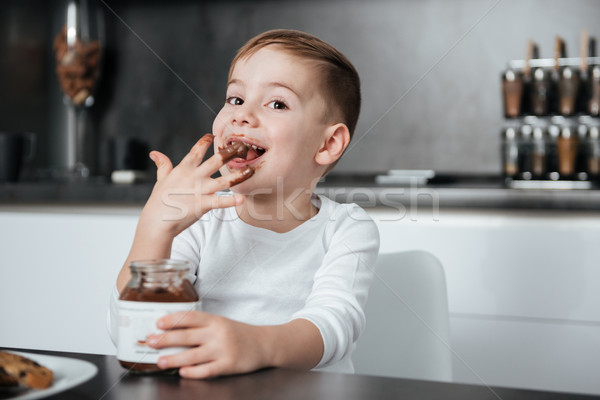 Cheerful boy standing in the kitchen while eating sweeties Stock photo © deandrobot